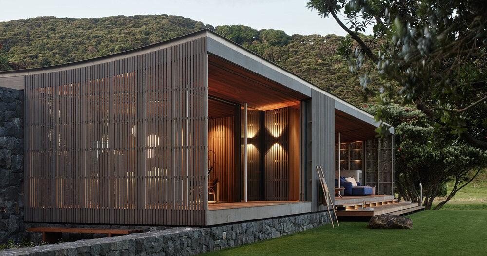 herbst architects’ omata beach house glows through a timber screen in new zealand