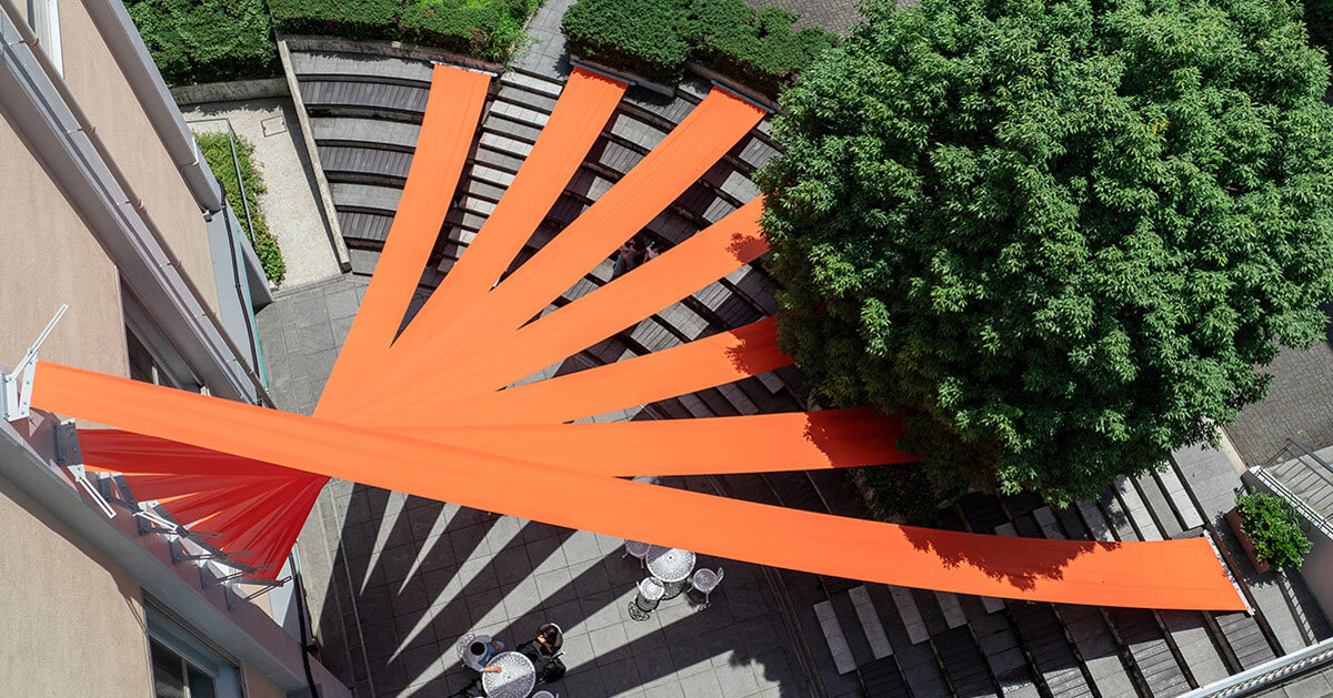 bright orange fabric panels fan out above university’s terraced amphitheater in japan