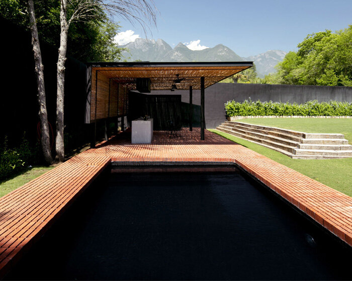 S-AR frames enigmatic black pool with red brick at outdoors pavilion in mexico