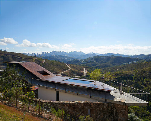 tetro tops residence with irregular deck roof opening towards mountainous views in brazil