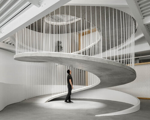 sculptural spiral staircase connects paulo merlini's warehouse turned office in portugal