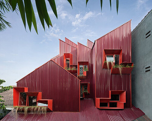 corrugated iron-clad stacked masses assemble this red house in indonesia