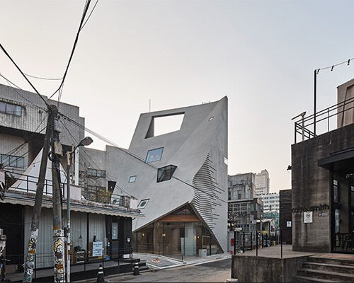 concrete pyramidoid spa with diverse cutouts stands out in the dense urban fabric of seoul