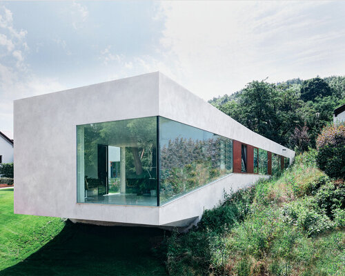 this german medical clinic sits as a protruding, off-white volume with dramatic glazing