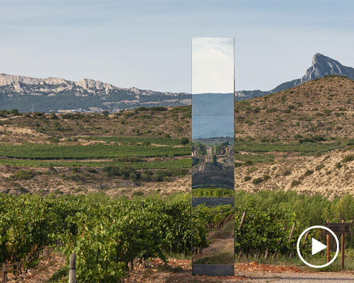 mirror-clad tower emerges as an ephemeral landmark within spanish vineyard