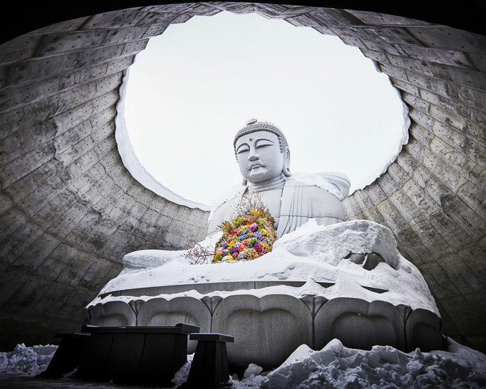 beneath tadao ando's hill, azuma makoto installs flower bouquet into arms of the buddha