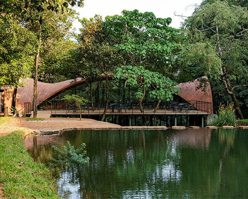 Dining space with vaulted brick canopy perches above a serene lake in India