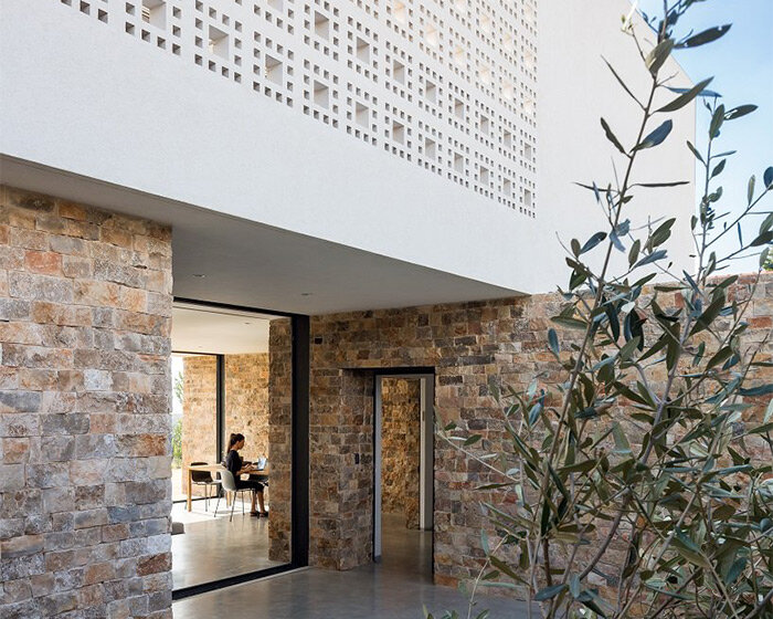 stone volumetry and checkered perforations articulate this minimalist house in israel