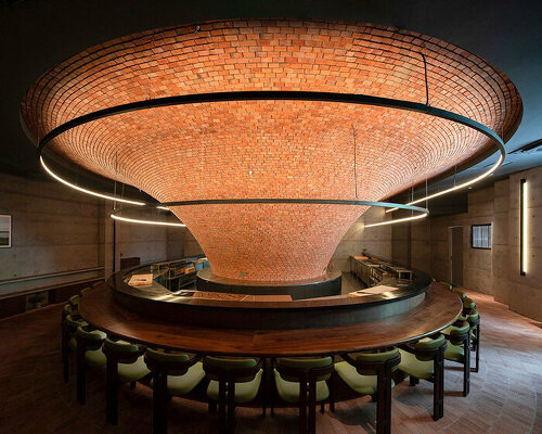 bar-like dining table encircles imposing raw brick funnel at yakitori restaurant in china