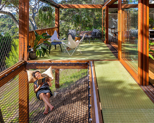 planted on a steep rocky slope, the 'balmy palmy' house in sydney celebrates simple living