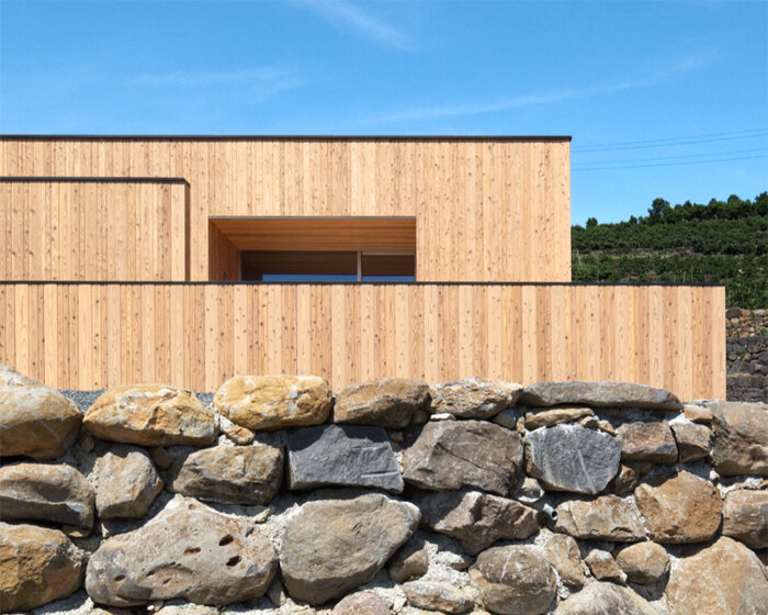 'house in tensui' emerges as a multi-layered wooden volume amid terraced fields in japan