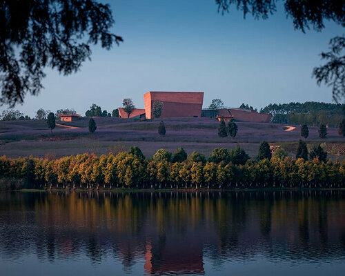 a cluster of red monolithic volumes by line+ makes up yunnan art center in china