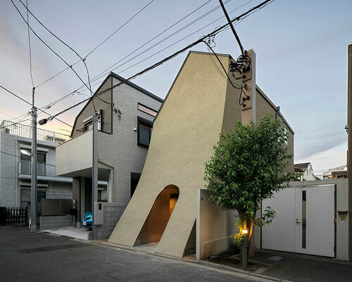 a sweeping introverted facade shelters a manga artist's split-leveled home studio in tokyo