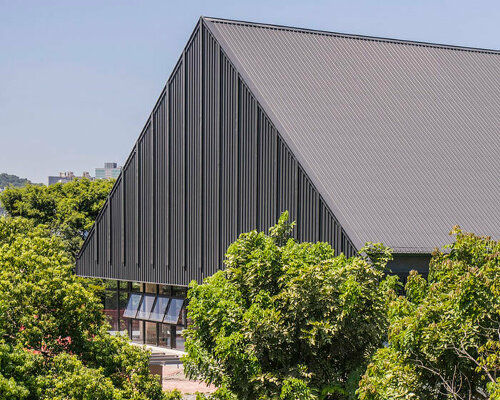 triangular metal roof crowns elevated sports hall in taiwan school extension