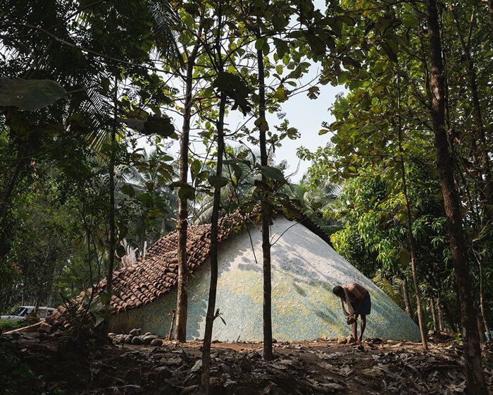 vaulted brick arches drape over earthen farmhouse nestled in indian forestscape