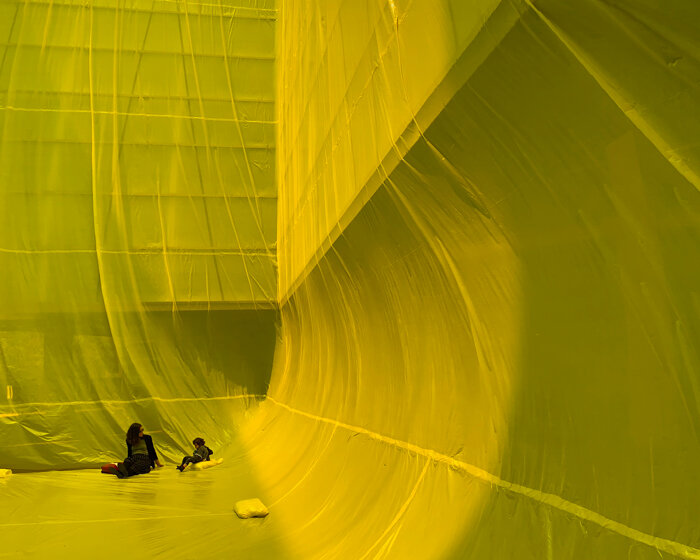 yellow inflatable installation squeezes into void space in barcelona