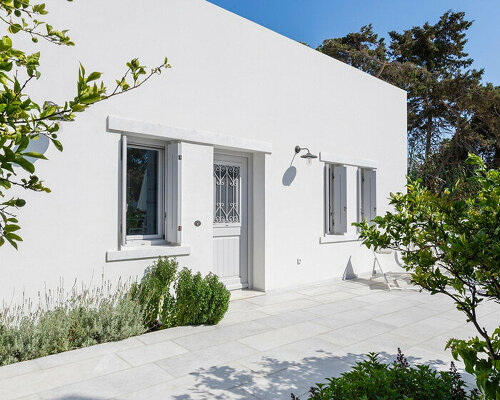 marble inlays adorn spolia house's pure white facade in greek island