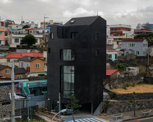 black mosaic tiles coat the organic shape of cultural facility in korea