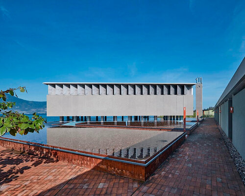 minimal concrete mosque floats above body of water in indonesia