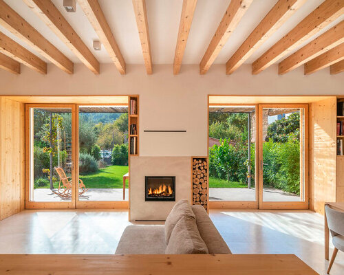 eco-passive house in spain exposes its wooden frame along with natural stone elements