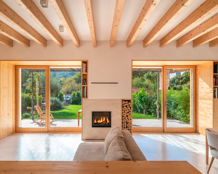 eco-passive house in spain exposes its wooden frame along with natural stone elements