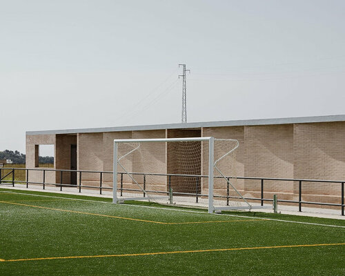 elongated brick-clad changing room completes small football field in seville