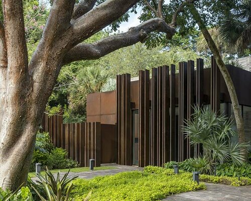 a corten steel gatehouse is overgrown by tropical nature in coconut grove, miami