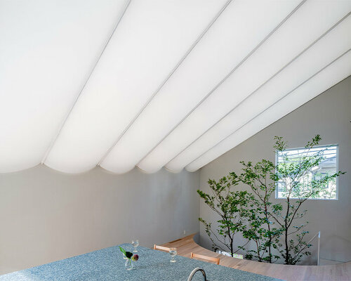 tubular membrane roof casts a soft glow over this two-story house in tokyo