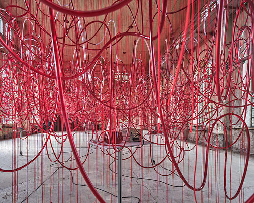 chiharu shiota's red intertwined tubes drift in former assembly hall in austria