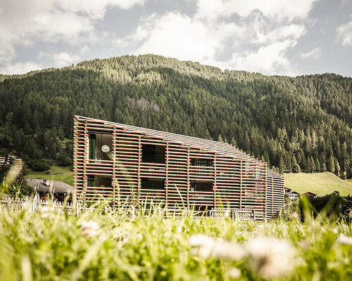 DEAR studio adapts old hay barns into modern larch log-clad hotel in italian alps