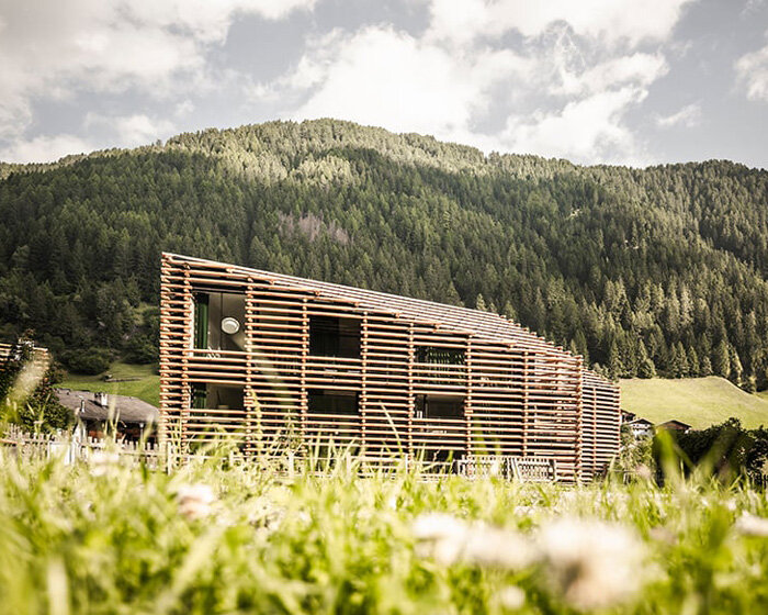 DEAR studio adapts old hay barns into modern larch log-clad hotel in italian alps