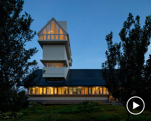 white tower pierces through the gable roof of silkworm house in vietnam