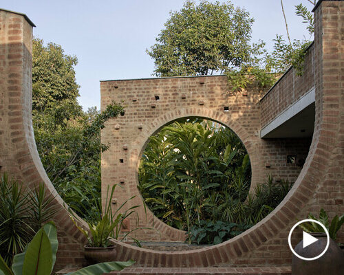 echoing ancient brick ruins, this public center in india peeps through a dense tropical flora