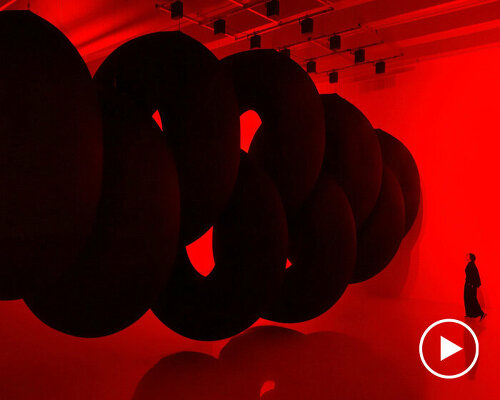 nine colossal tubes undulate and dwarf visitors amid a red glow in SpY's beijing installation