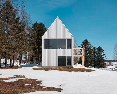 white cladding envelops la musette gabled village hut in canadian hillside