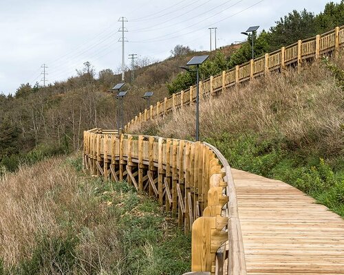 pedestrian wooden walkway on stilts traces hillside in bilbao