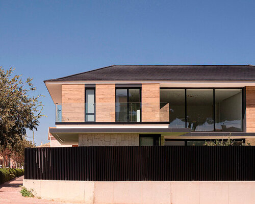 distinct black tiling and hewn stone clad two-story residence in spain