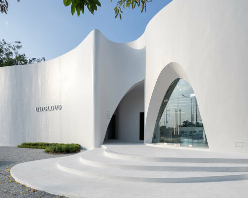 uncloud coffee's arching white structure integrates smoothly into its surroundings in thailand