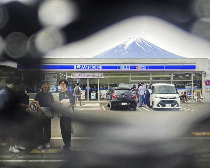 tourists poke holes into fence for the perfect photo at restricted mt. fuji