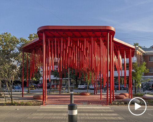 melodic tubes sway in the wind, inviting pedestrians to vibrant red pavilion in mexico