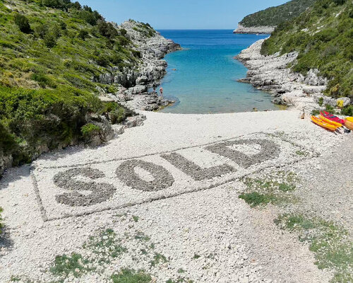 dark stones spell SOLD on greek beach in protest against coastal development