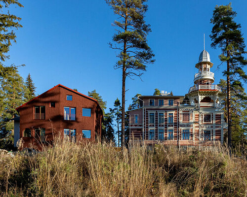 ornamental wooden castle in finland restored with red-shingled guest house