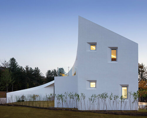 curvilinear house in south korea sweeps toward the ground with fluid facade