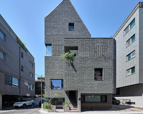 a round architects sculpts seoul office building with dark, rusticated stone bricks