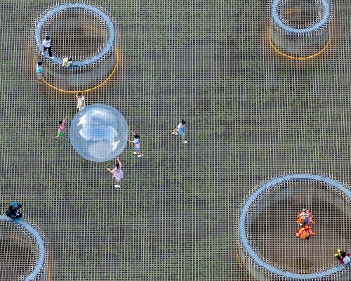 zxd architects stretches large woven net across pond in rural china, inviting rest and play