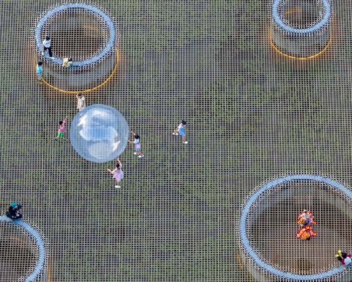 zxd architects stretches large woven net across pond in rural china, inviting rest and play