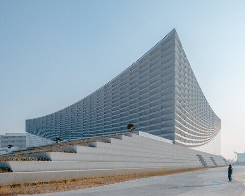 beijing performing arts centre rises from broad plinth like parting theater curtains