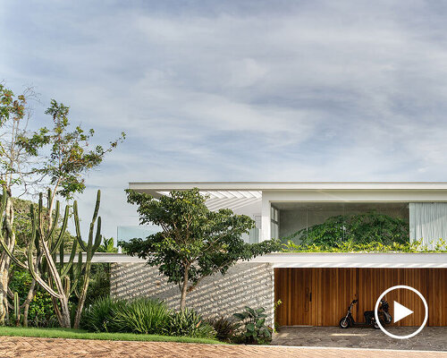 two vertical planes of white wood stone enfold casa búzios' volumes in rio de janeiro