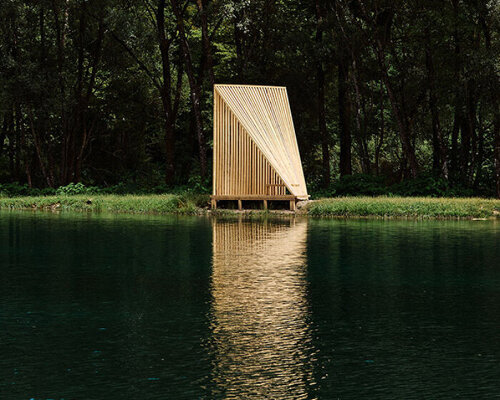 triangular wooden cabin unfolds on river's shore near alps as a fishermen's retreat