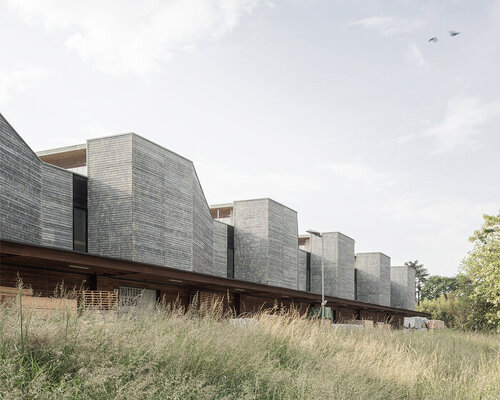 seven wood-clad boxes set in rhythmic sequence outline industrial building's facade in italy